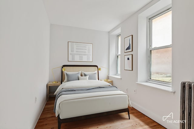 bedroom with radiator and wood finished floors