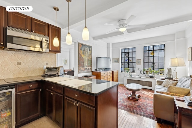25 Tudor City Pl Unit 1812, New York City, NY 10017 - kitchen featuring stainless steel microwave, beverage cooler, open floor plan, radiator, and tasteful backsplash