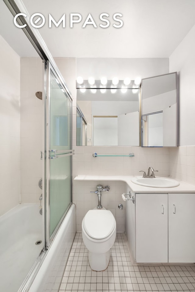 301 E 64th St Unit 4J, New York City, NY 10065 - bathroom featuring tile patterned floors, shower / bath combination with glass door, toilet, tile walls, and vanity
