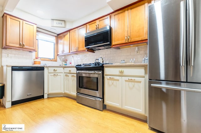 93 3rd St, New York City, NY 11231 - kitchen featuring appliances with stainless steel finishes, light wood-style floors, decorative backsplash, and light stone countertops