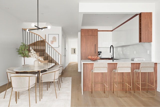 kitchen with brown cabinetry, light countertops, a sink, light wood-type flooring, and modern cabinets