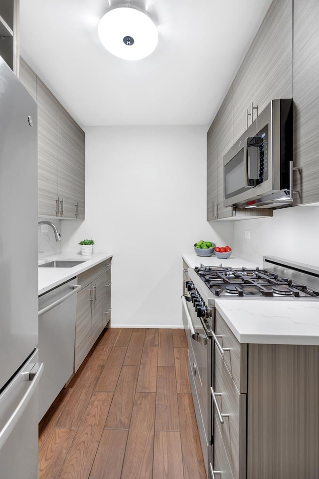 kitchen featuring stainless steel appliances, a sink, gray cabinetry, and modern cabinets