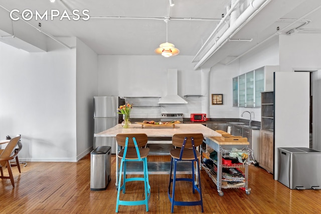 565 Broadway Unit 8W, New York City, NY 10012 - kitchen featuring wall chimney range hood, freestanding refrigerator, light wood-type flooring, and a center island