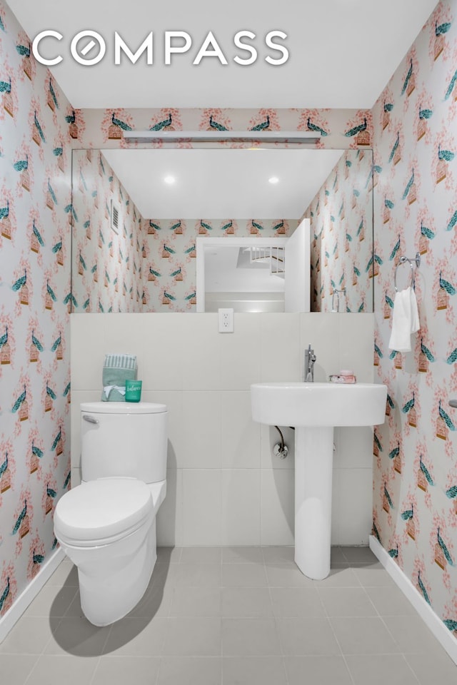 bathroom featuring baseboards, tile patterned flooring, toilet, and wallpapered walls
