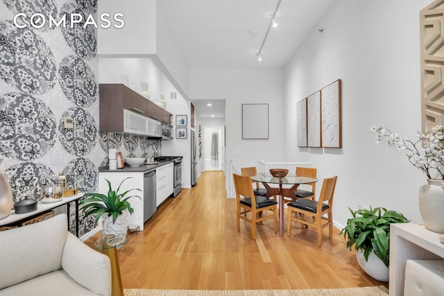 dining area with baseboards, light wood-type flooring, rail lighting, and visible vents