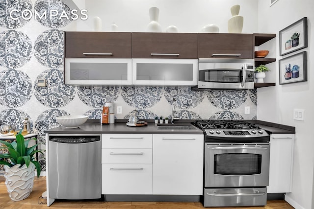 kitchen featuring dark countertops, modern cabinets, tasteful backsplash, a sink, and stainless steel appliances