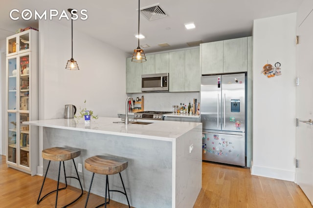 kitchen with a sink, stainless steel appliances, light wood-type flooring, and visible vents