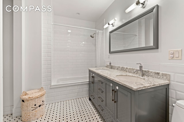 bathroom featuring double vanity, a sink, tiled shower / bath, and toilet