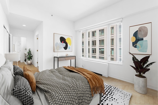 bedroom featuring baseboards, radiator heating unit, and multiple windows
