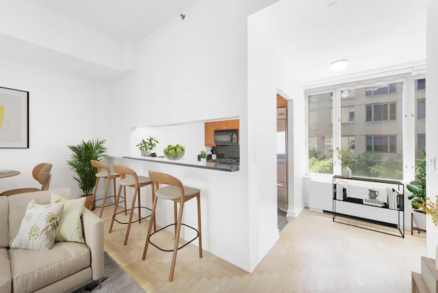 kitchen featuring baseboards, a peninsula, black microwave, and a breakfast bar