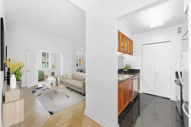 kitchen with visible vents, white dishwasher, a sink, and brown cabinets