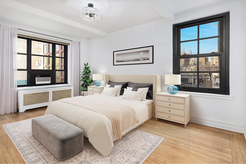 bedroom with radiator, light wood finished floors, beam ceiling, and baseboards