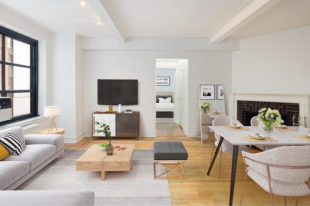 living room with a fireplace, light wood-style floors, beamed ceiling, and baseboards