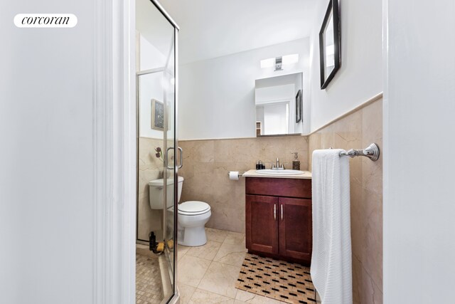 203 W 122nd St Unit 4, New York City, NY 10027 - bathroom with tile walls, a shower stall, vanity, toilet, and a wainscoted wall