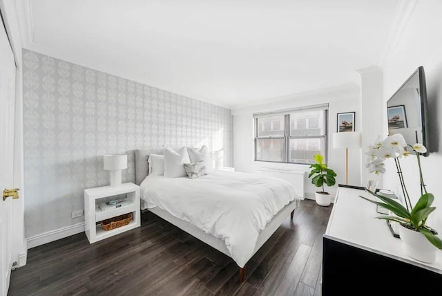 bedroom featuring an accent wall, wallpapered walls, dark wood-style flooring, and baseboards