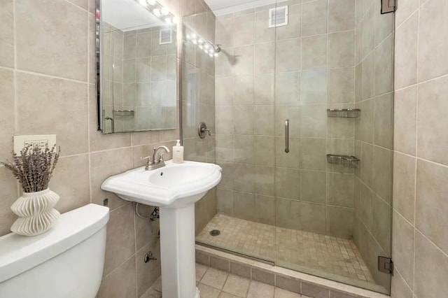 bathroom with tile walls, visible vents, a shower stall, and toilet