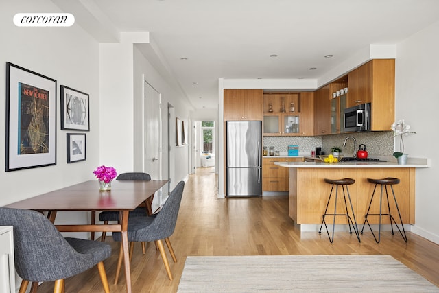 kitchen with light wood-style floors, appliances with stainless steel finishes, and brown cabinets