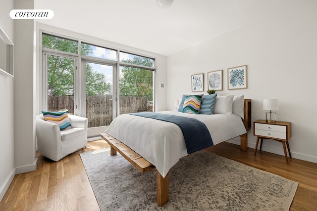 bedroom with light wood-style floors, multiple windows, and access to exterior