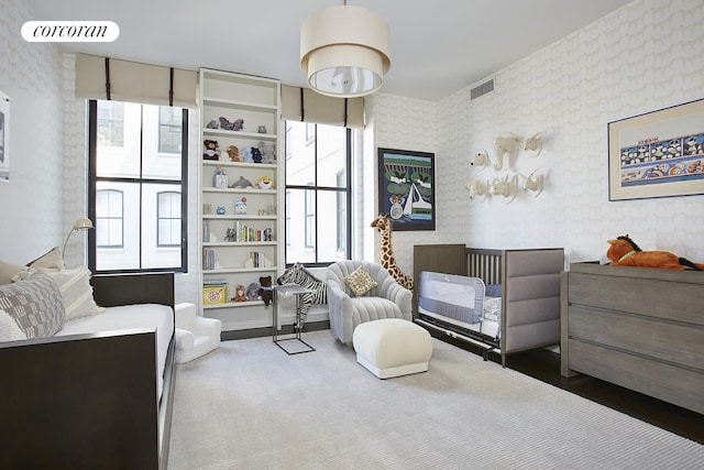 bedroom featuring visible vents, wallpapered walls, and wood finished floors