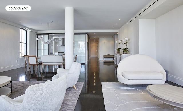 living area featuring a notable chandelier, wood finished floors, visible vents, and baseboards