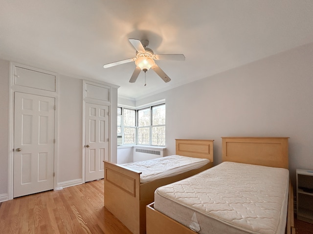 bedroom with baseboards, a ceiling fan, light wood-style flooring, and radiator
