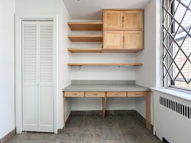 interior space with built in study area, baseboards, and radiator heating unit