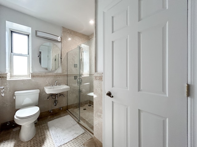 bathroom with a sink, tile walls, a shower stall, and toilet