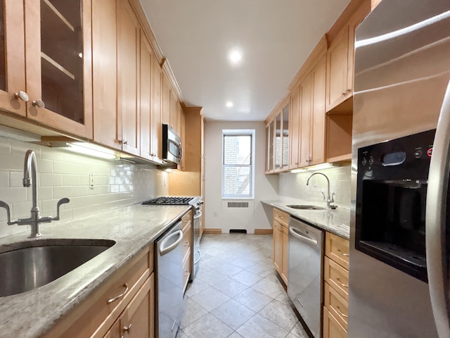 kitchen featuring baseboards, a sink, tasteful backsplash, and stainless steel appliances