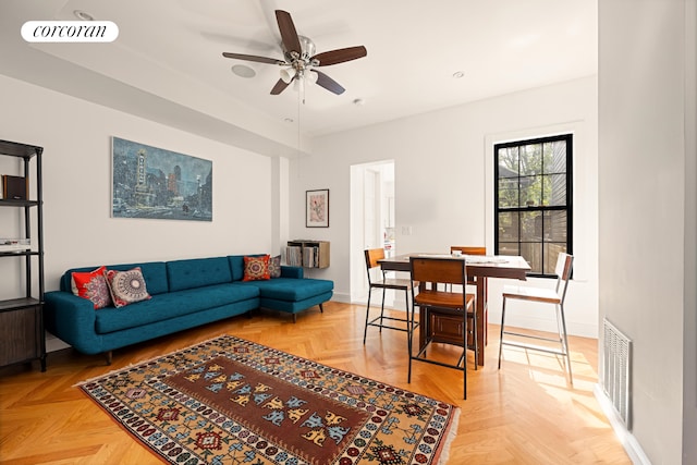 living room with baseboards, ceiling fan, and visible vents