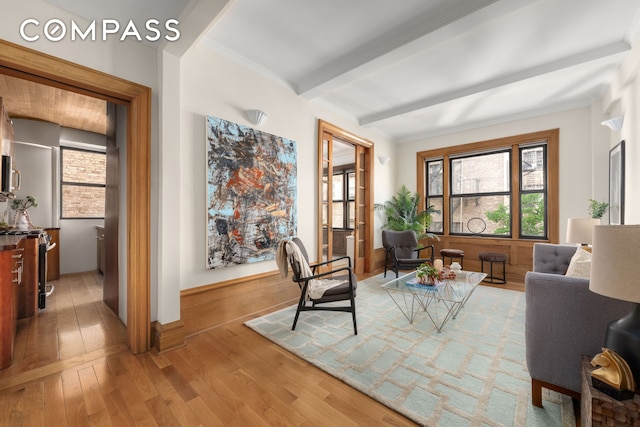 living area with beamed ceiling, a wealth of natural light, and light wood-style flooring