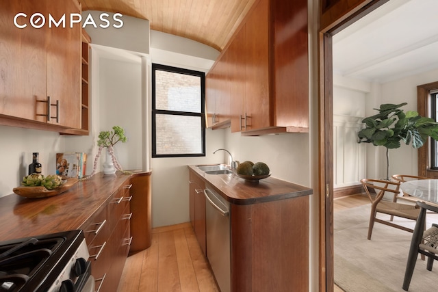 kitchen featuring brown cabinetry, vaulted ceiling, light wood-type flooring, a sink, and stainless steel appliances