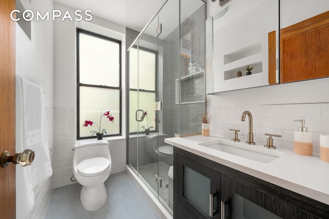 bathroom featuring tile walls, tile patterned flooring, a shower stall, vanity, and toilet