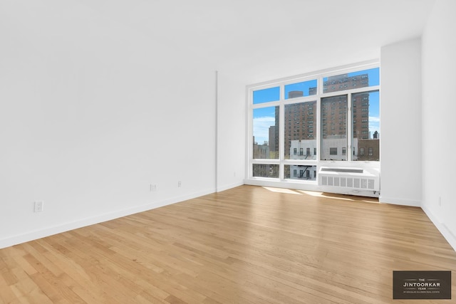333 E 109th St Unit 6B, New York City, NY 10029 - spare room with a city view, light wood-style floors, expansive windows, baseboards, and radiator