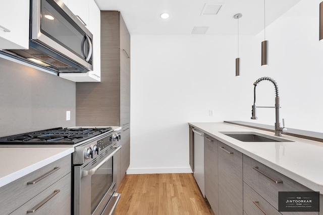 333 E 109th St Unit 6B, New York City, NY 10029 - kitchen with stainless steel appliances, a sink, modern cabinets, light wood finished floors, and gray cabinetry