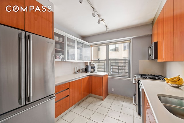 kitchen with light countertops, stainless steel appliances, brown cabinets, and glass insert cabinets