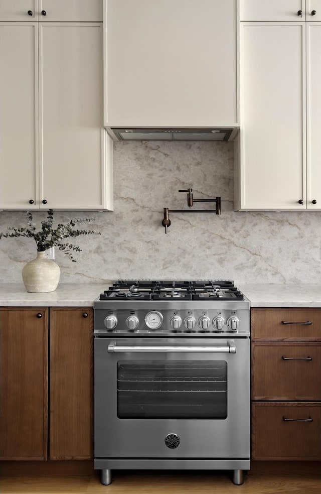 kitchen with white cabinets, stainless steel range, and tasteful backsplash