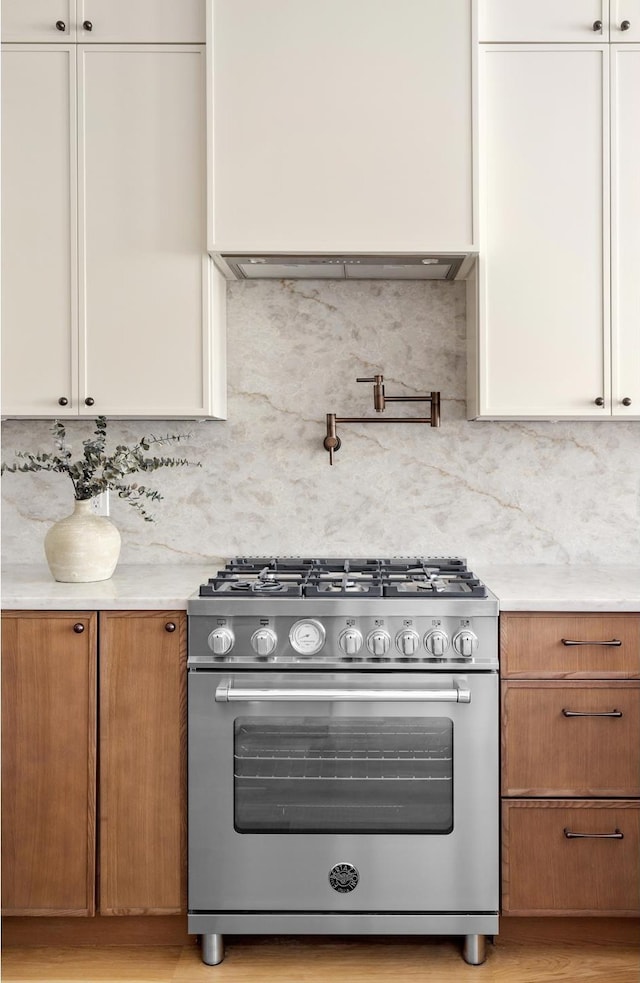 kitchen featuring decorative backsplash, high end stainless steel range, brown cabinets, and white cabinets