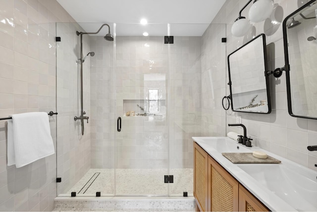 full bathroom featuring double vanity, tile walls, a sink, and a stall shower