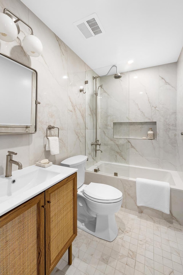 full bath featuring visible vents, tile walls, a combined bath / shower with marble appearance, vanity, and toilet
