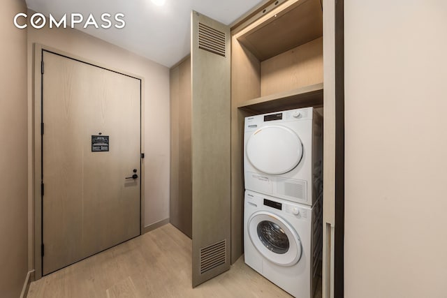 washroom featuring stacked washer and clothes dryer, laundry area, and light wood finished floors