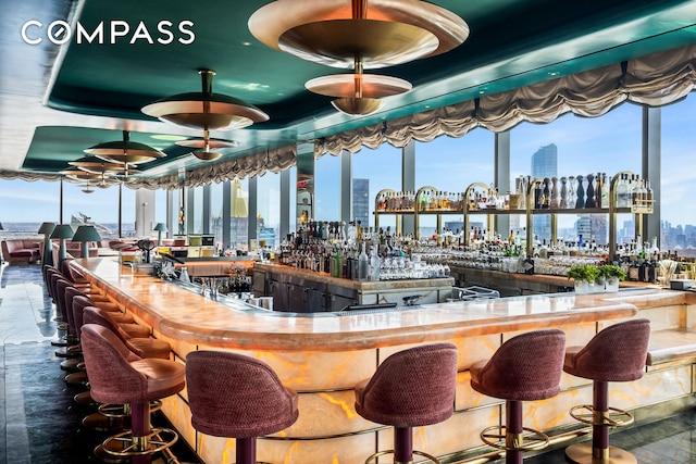 bar featuring a view of city, ceiling fan, a community bar, and plenty of natural light