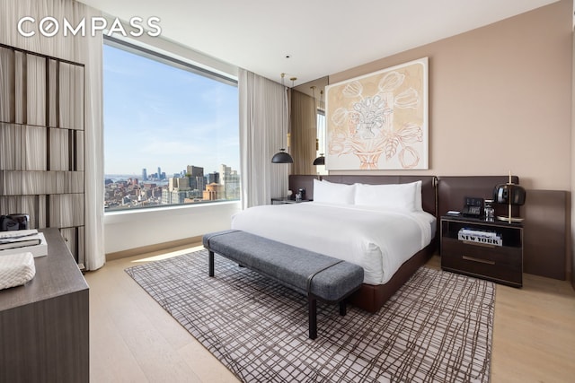 bedroom with light wood-style floors and a city view