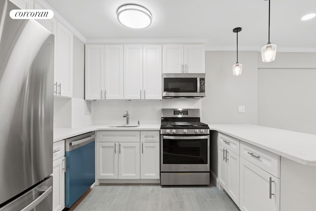 kitchen featuring stainless steel appliances, a sink, a peninsula, light countertops, and white cabinetry