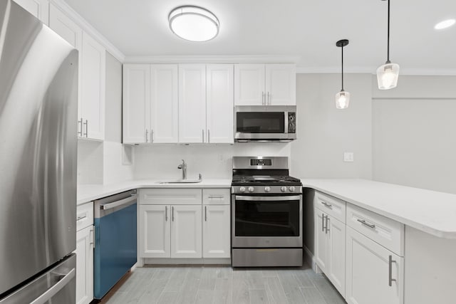 kitchen featuring stainless steel appliances, light countertops, a sink, white cabinetry, and a peninsula
