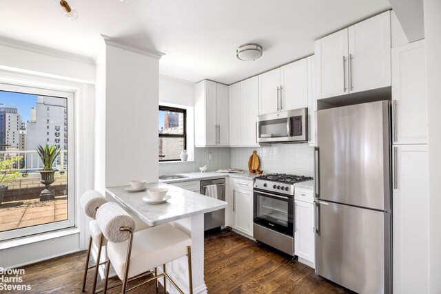 kitchen featuring tasteful backsplash, a breakfast bar area, stainless steel appliances, and white cabinetry