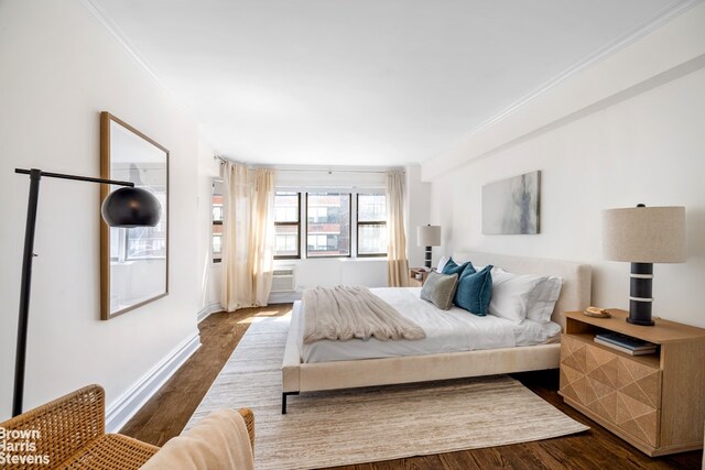 bedroom with crown molding, baseboards, and dark wood-style floors