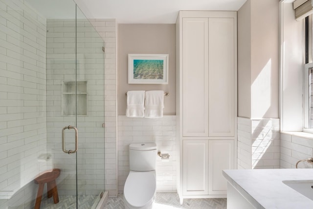 full bath with tile walls, a stall shower, toilet, and vanity
