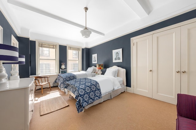 bedroom with light carpet, beamed ceiling, and a closet