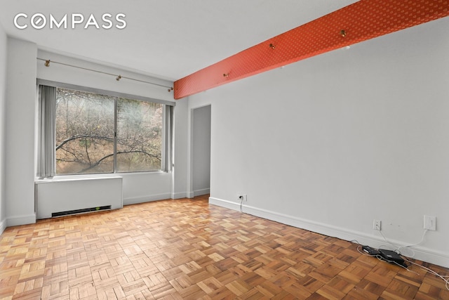 spare room with baseboards and radiator heating unit