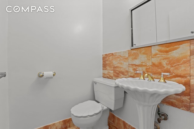 half bath featuring toilet, a sink, and tasteful backsplash